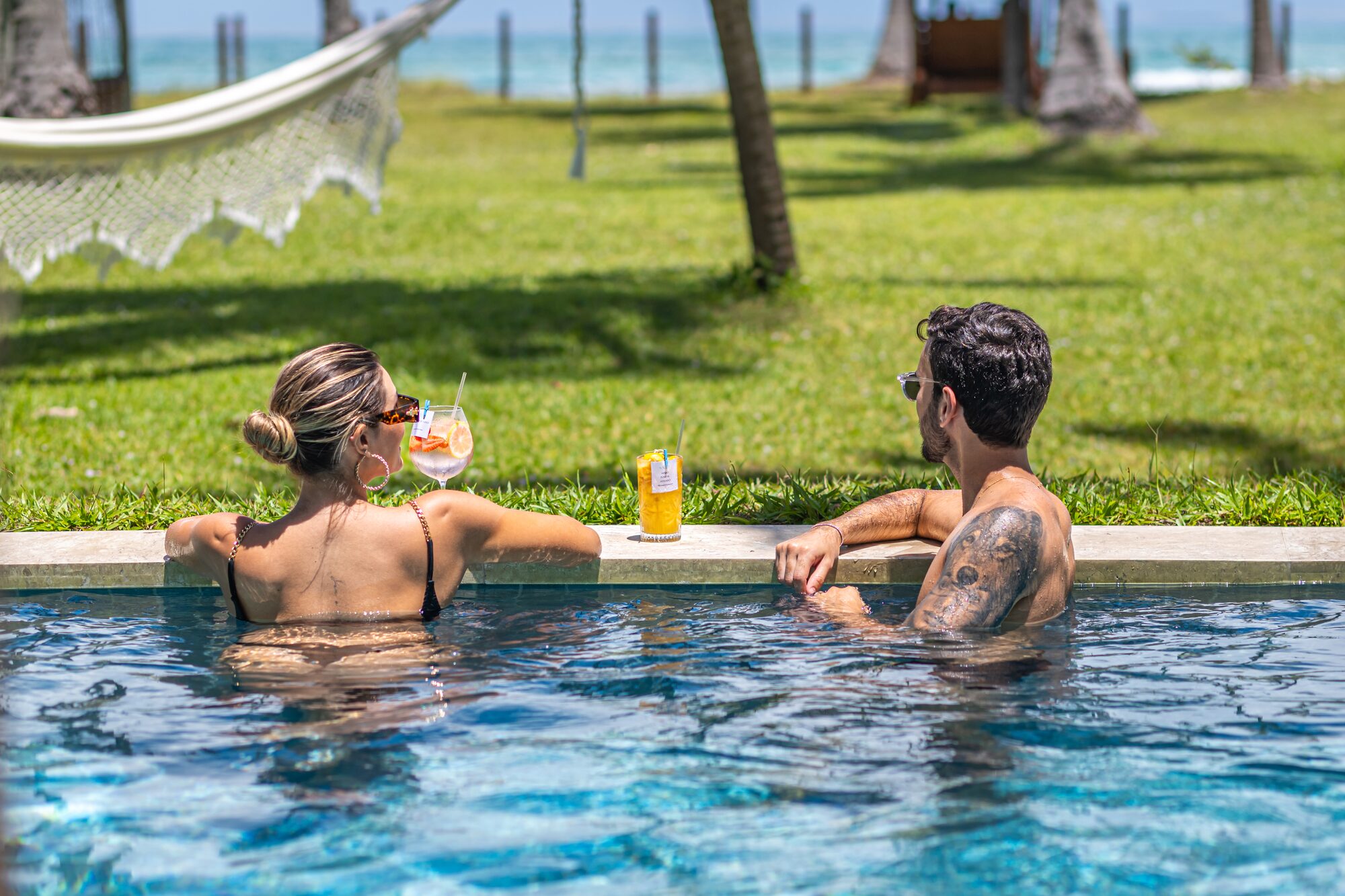 Casal na piscina privativa do bangalow com vista para o mar
