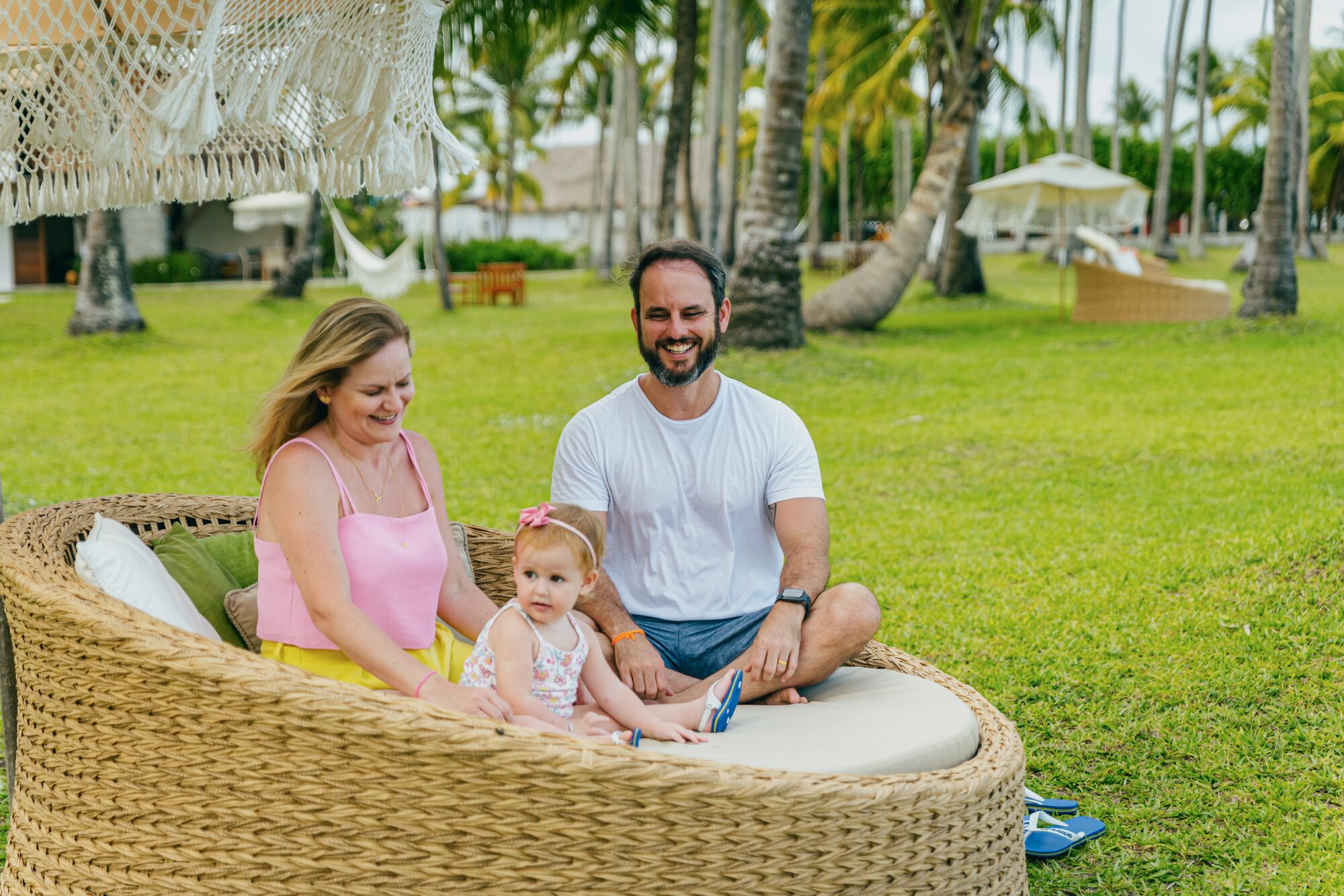 Família relaxando em daybed entre coqueiros no Pontal
